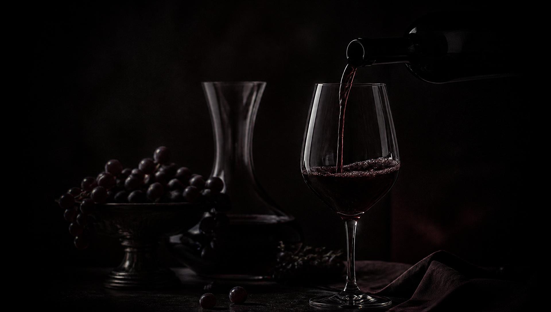 Vino tinto servido en copa de cristal en penumbra